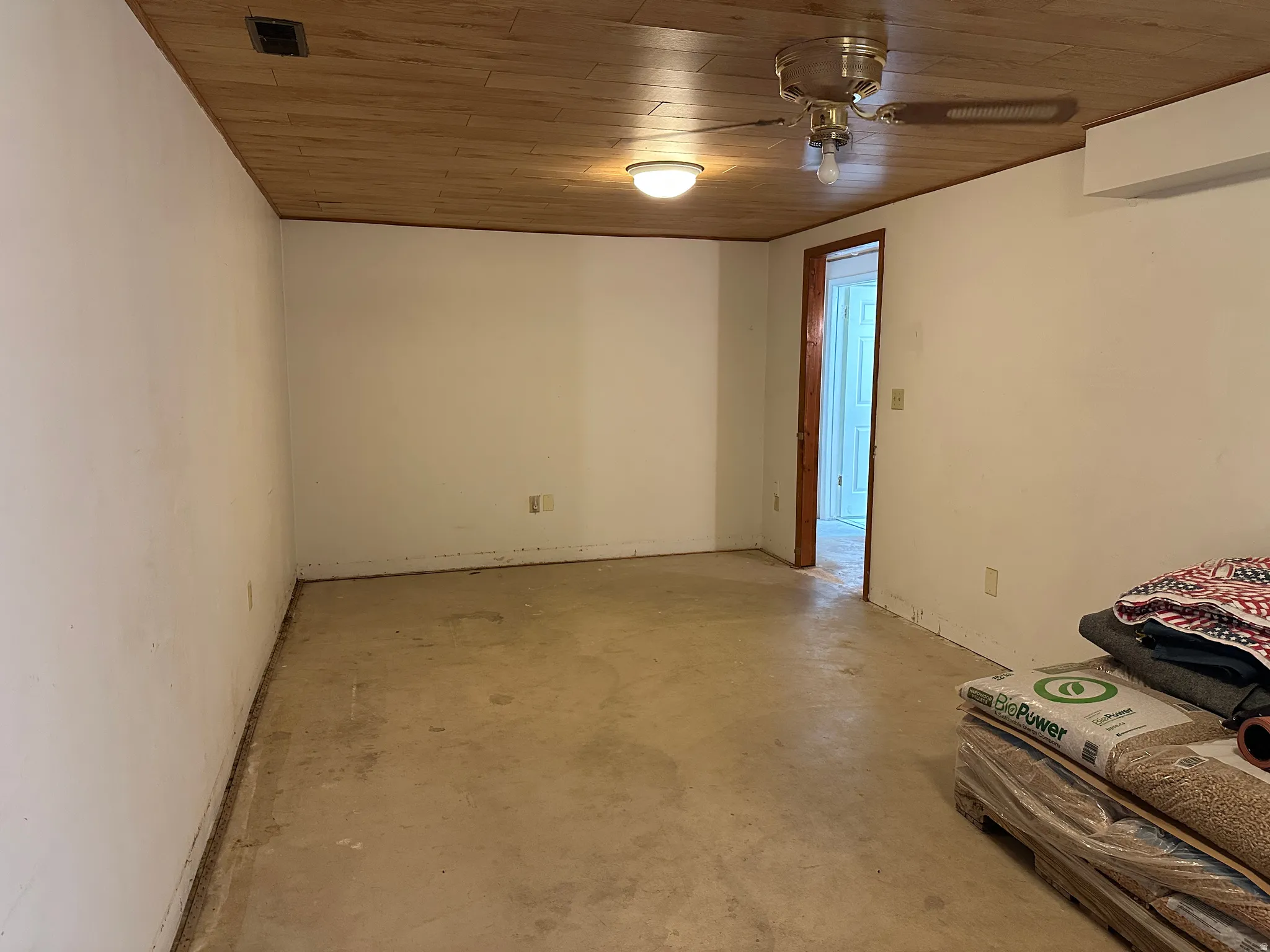 Room with wood-finish ceiling, white walls, and concrete flooring