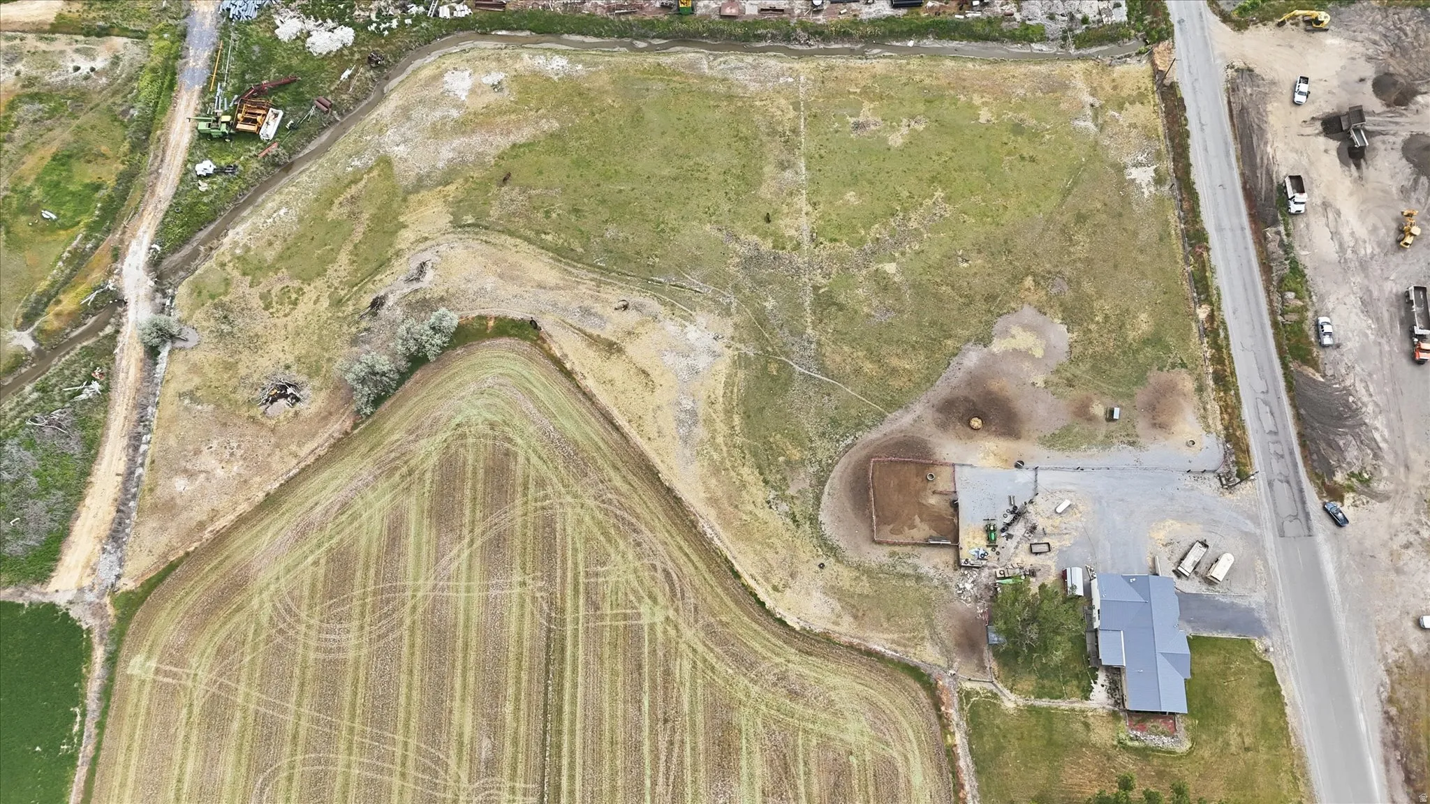 Expansive property featuring a residence with metal roof, a fenced area, and agricultural land