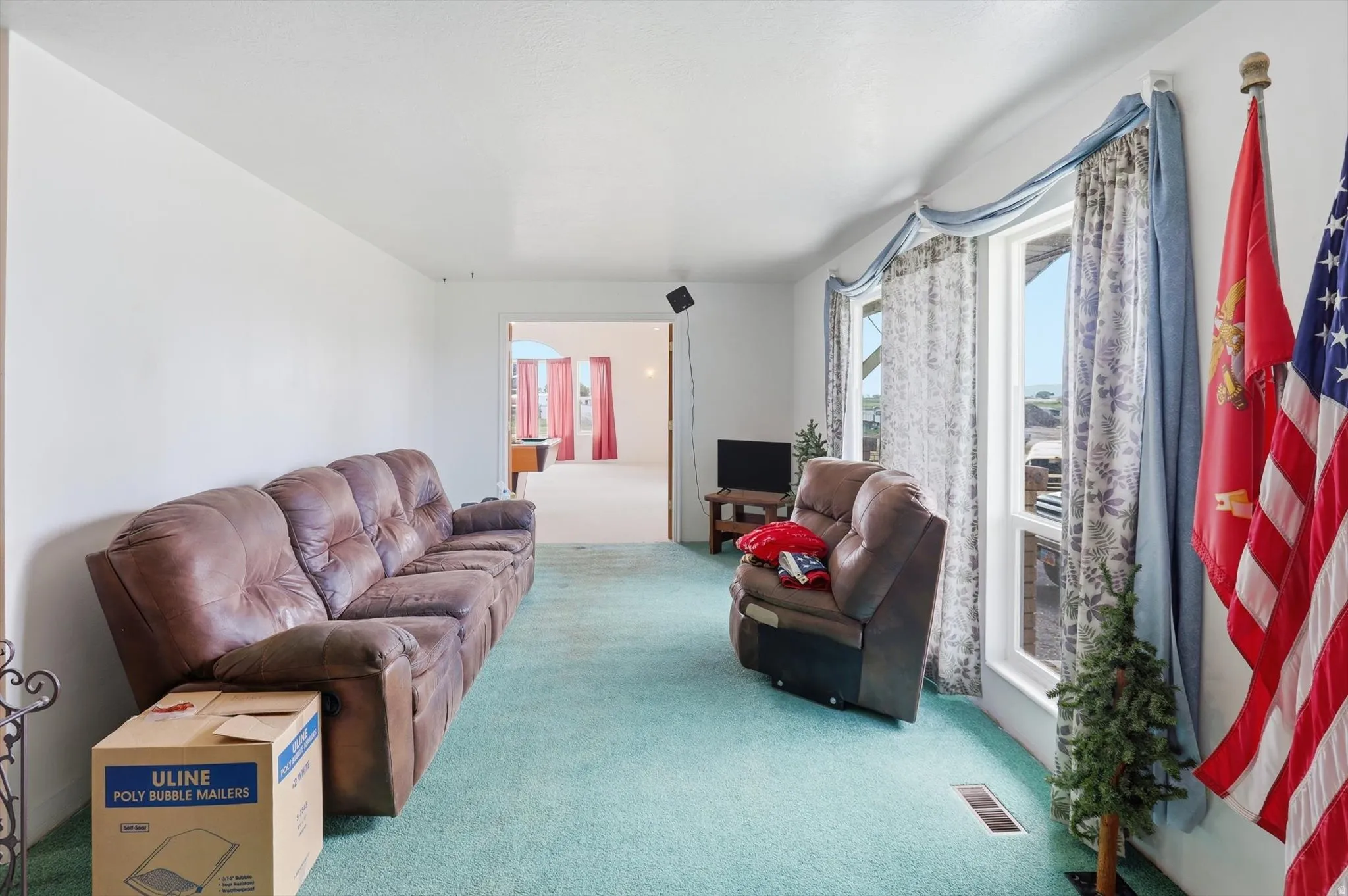 Spacious room featuring light blue carpeting and white walls