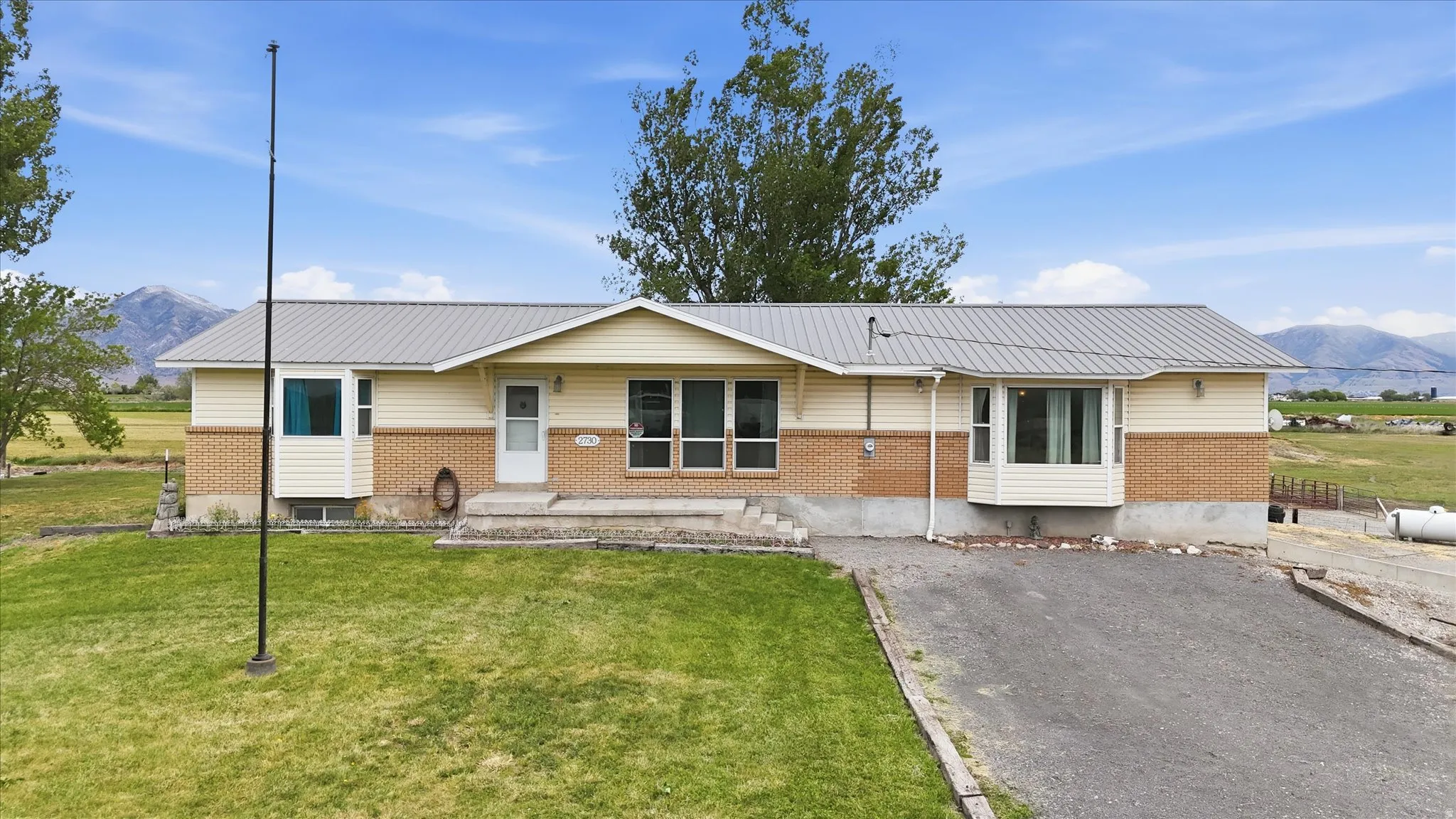 Residence featuring a metal roof, brick and siding exterior, and a gravel driveway