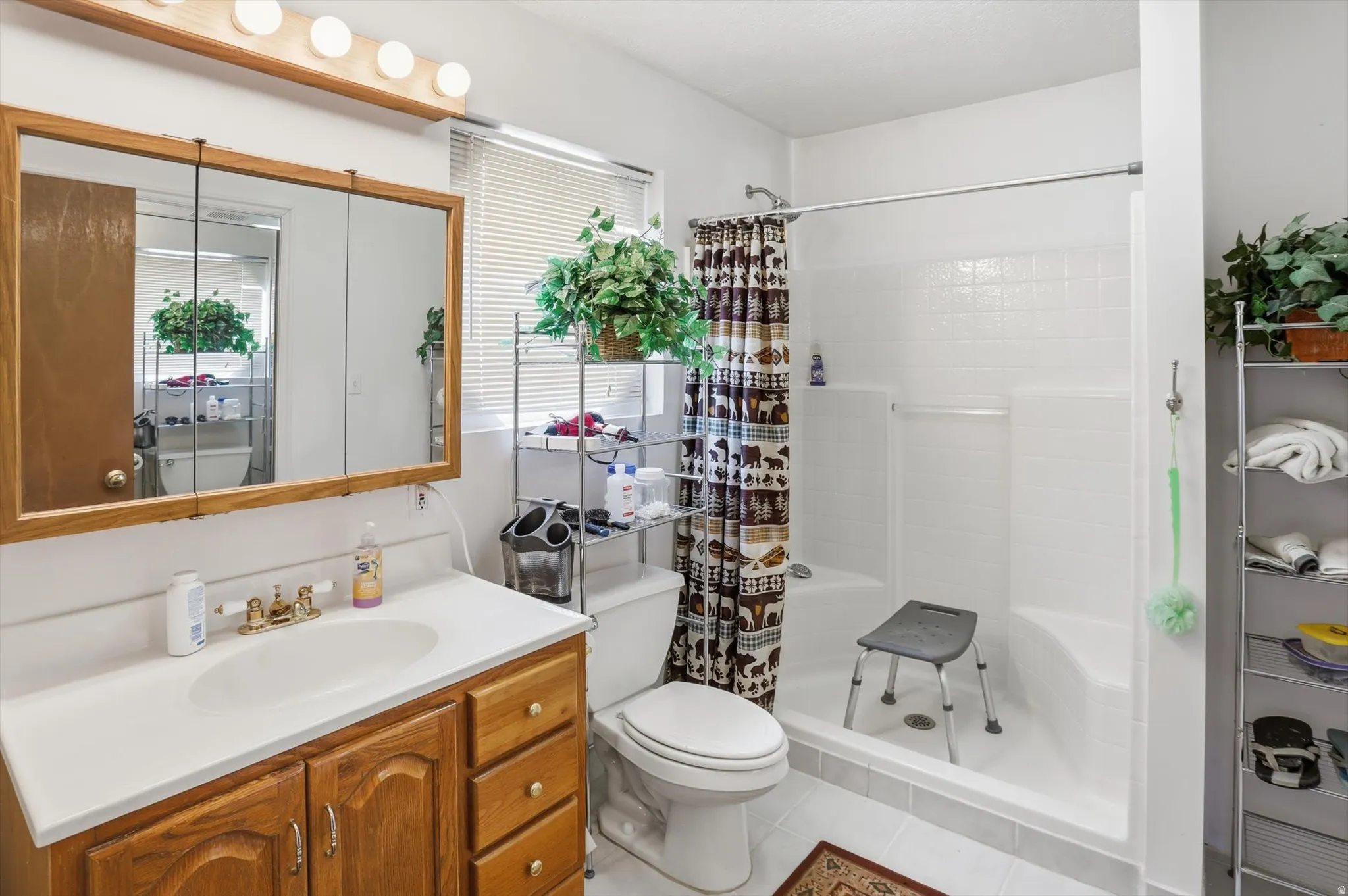 Bathroom featuring a wood-finish vanity with an integrated sink, a large mirrored medicine cabinet, and a shower with white tile surround