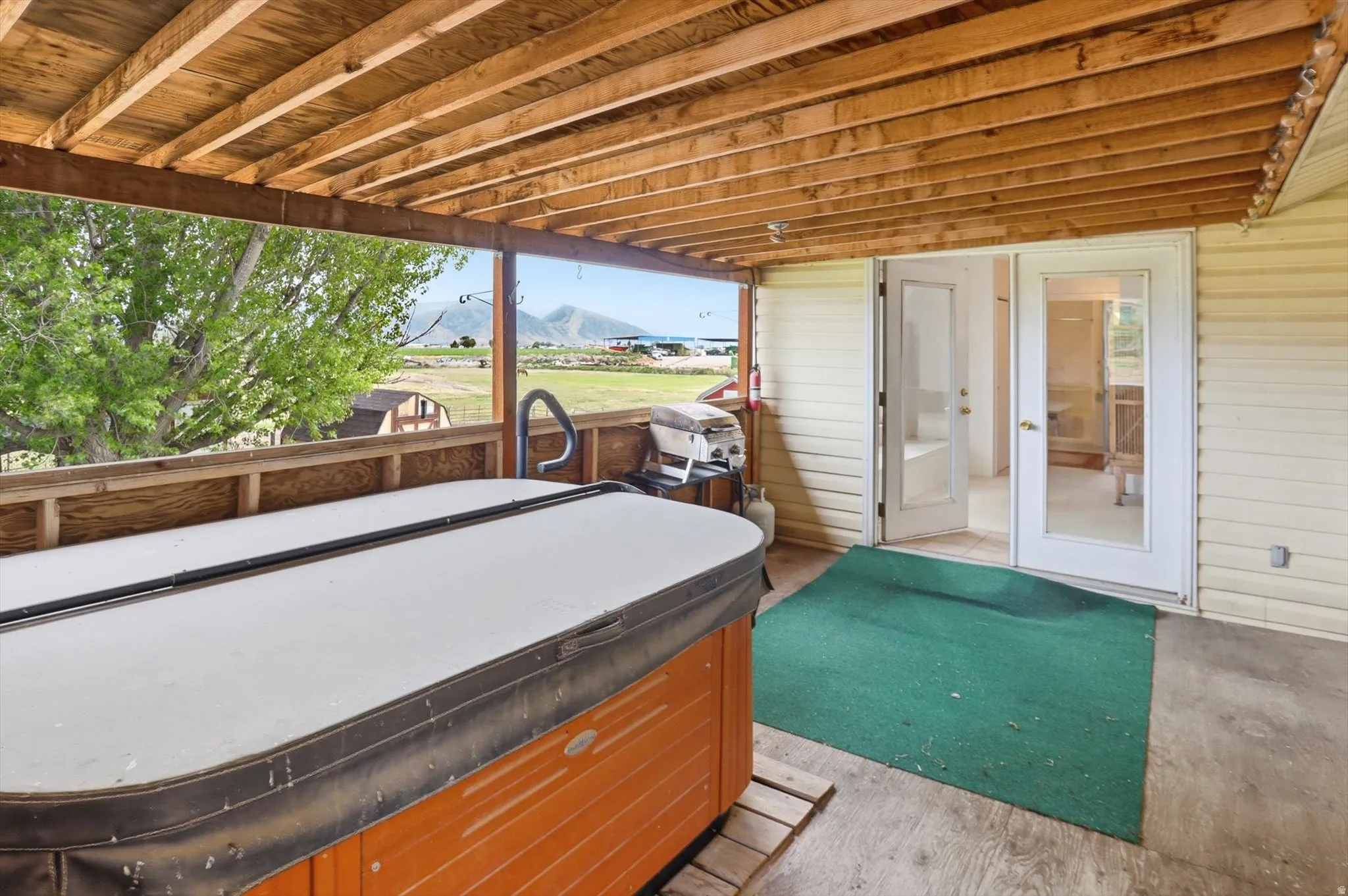 Covered patio with exposed wood ceiling beams, and entry to recreation room