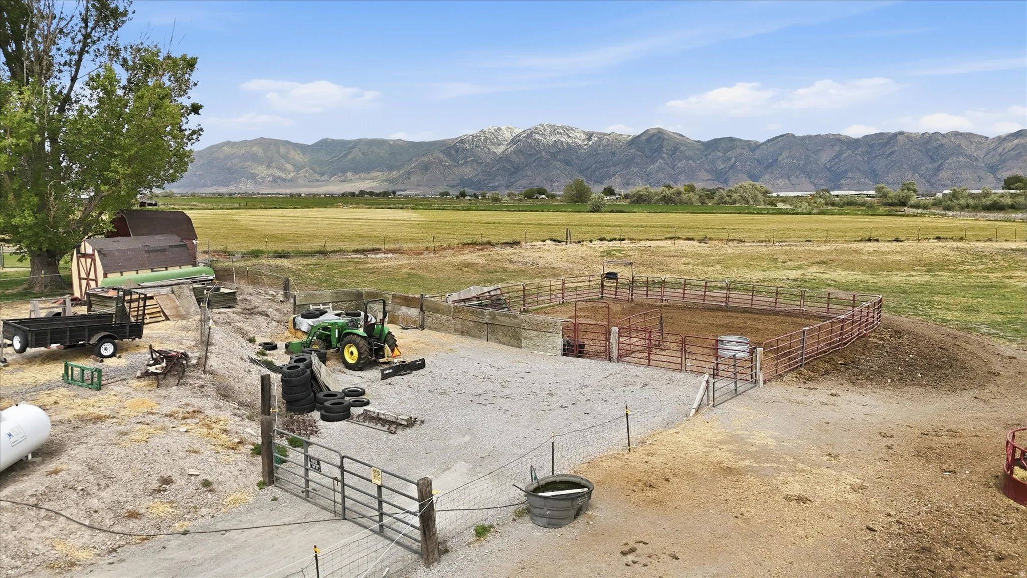 Expansive outdoor area featuring a barn with a gambrel roof and a fenced animal pen