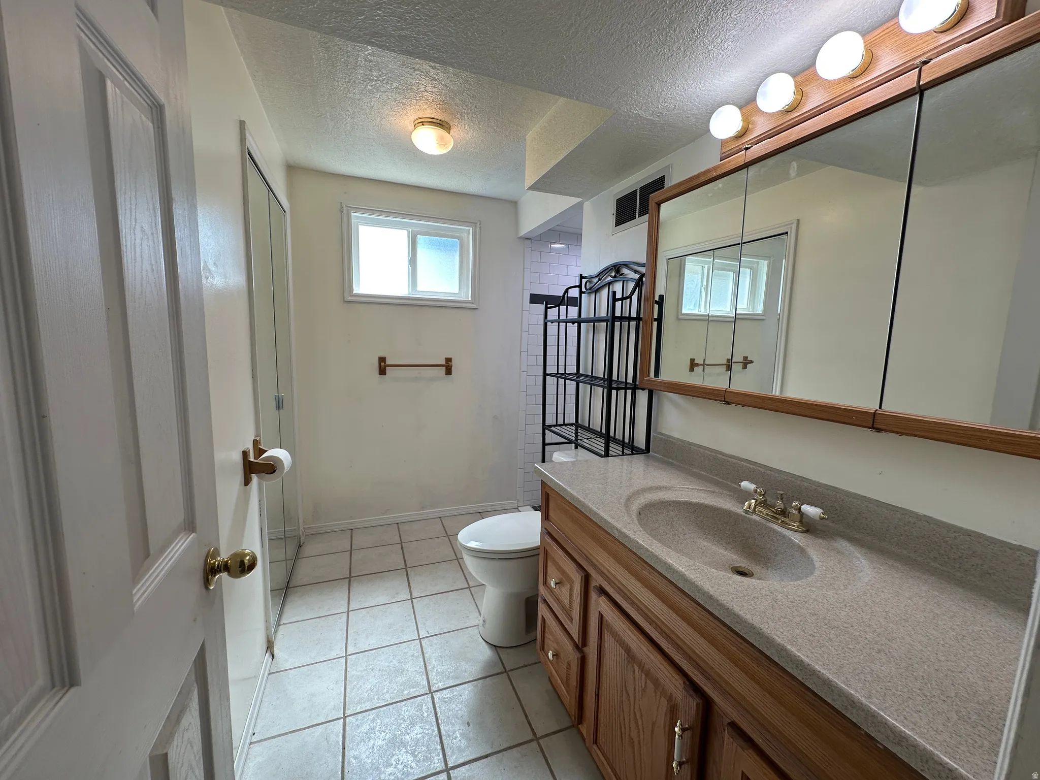 Bathroom featuring a window, tile flooring, and a single vanity with an integrated sink