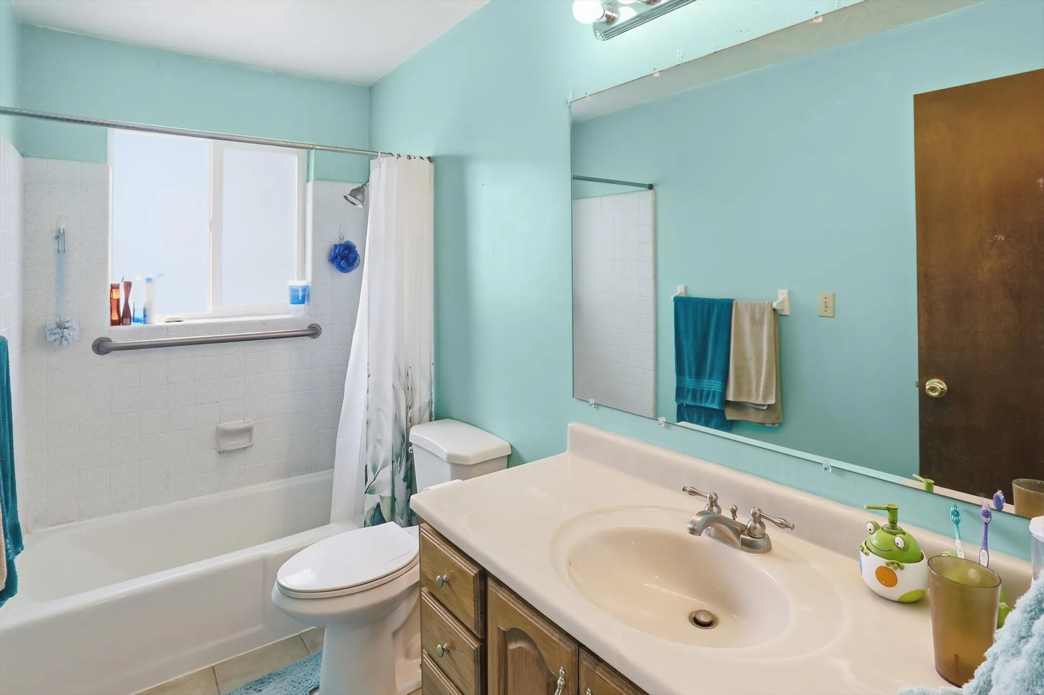 Bathroom featuring a white bathtub, ceramic tile surround, a built-in window, and grab bar
