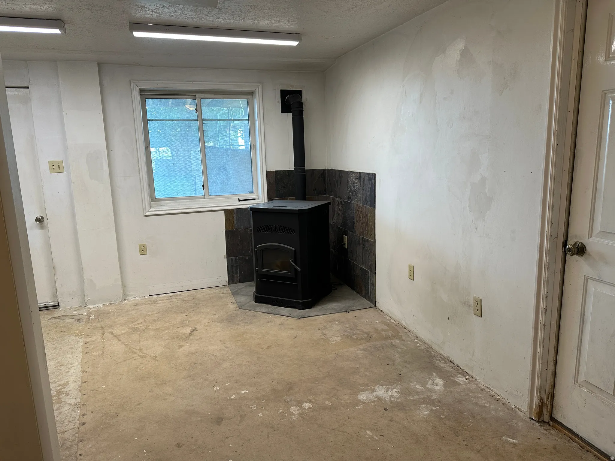 Room featuring a dark-toned freestanding stove on a stone tile hearth, set against a stone tile wall surround