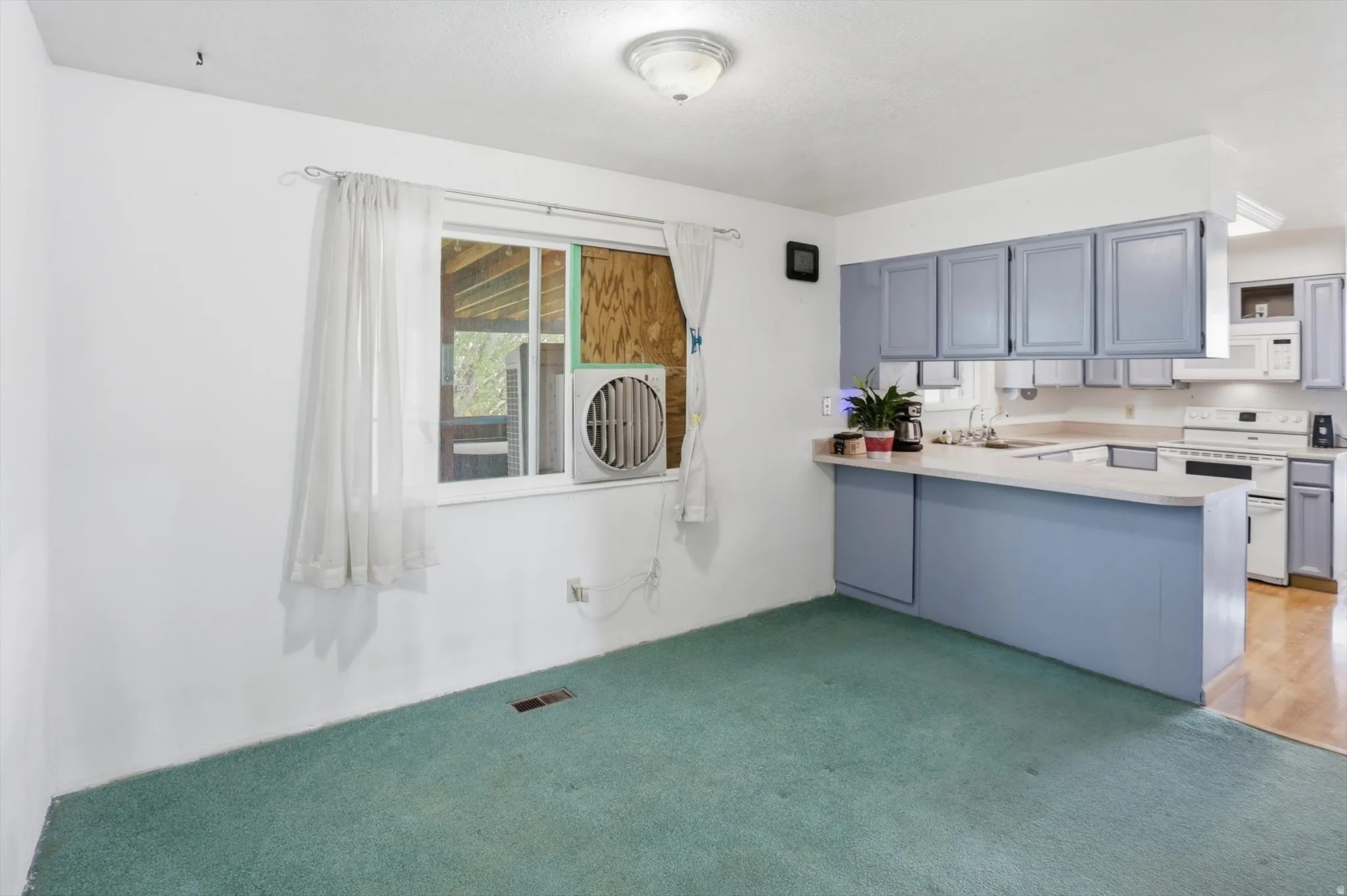 Kitchen area featuring light blue cabinetry, light-toned countertops, and white appliances