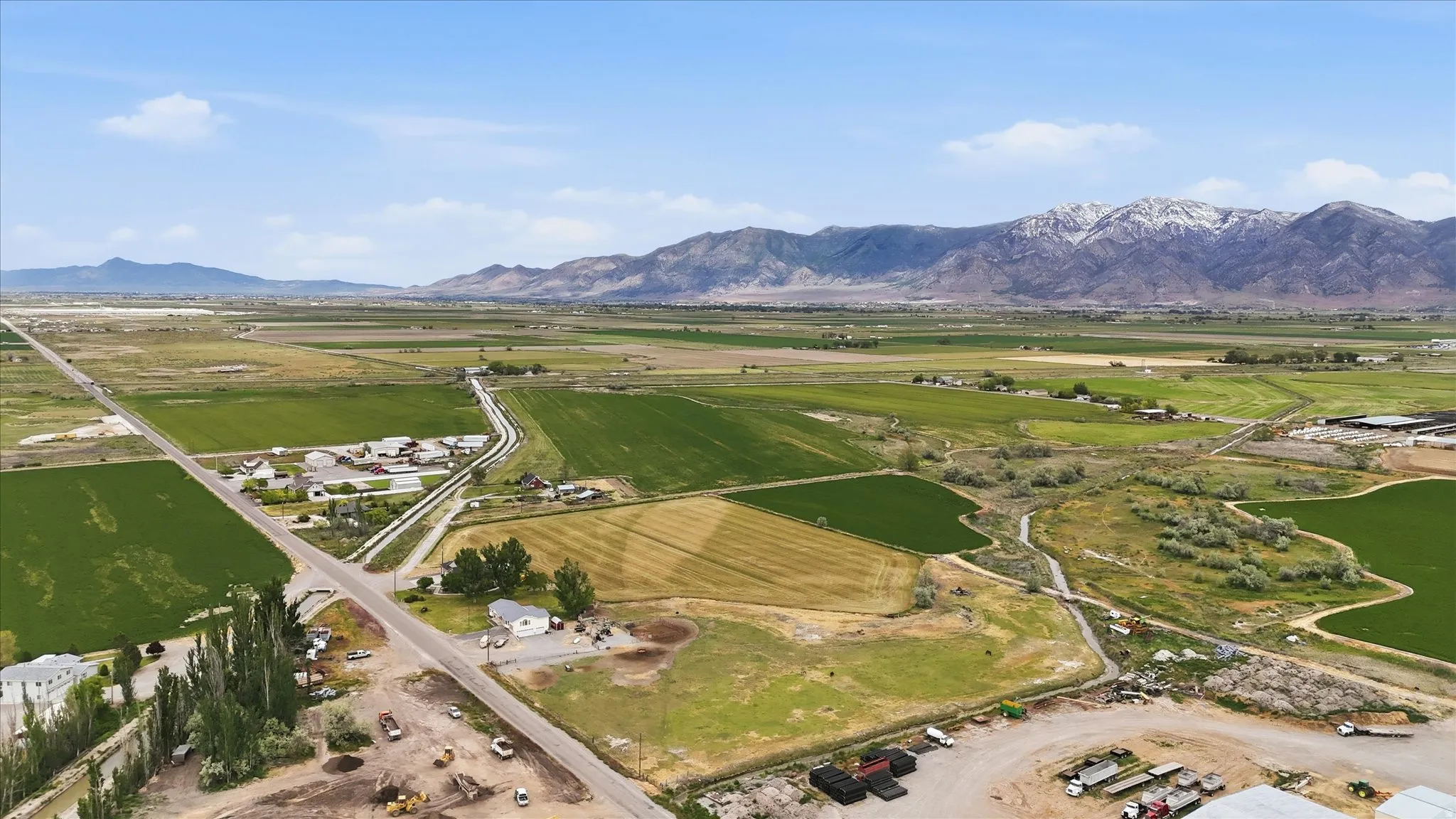 Expansive rural landscape featuring a prominent mountain range with snow-capped peaks in the background