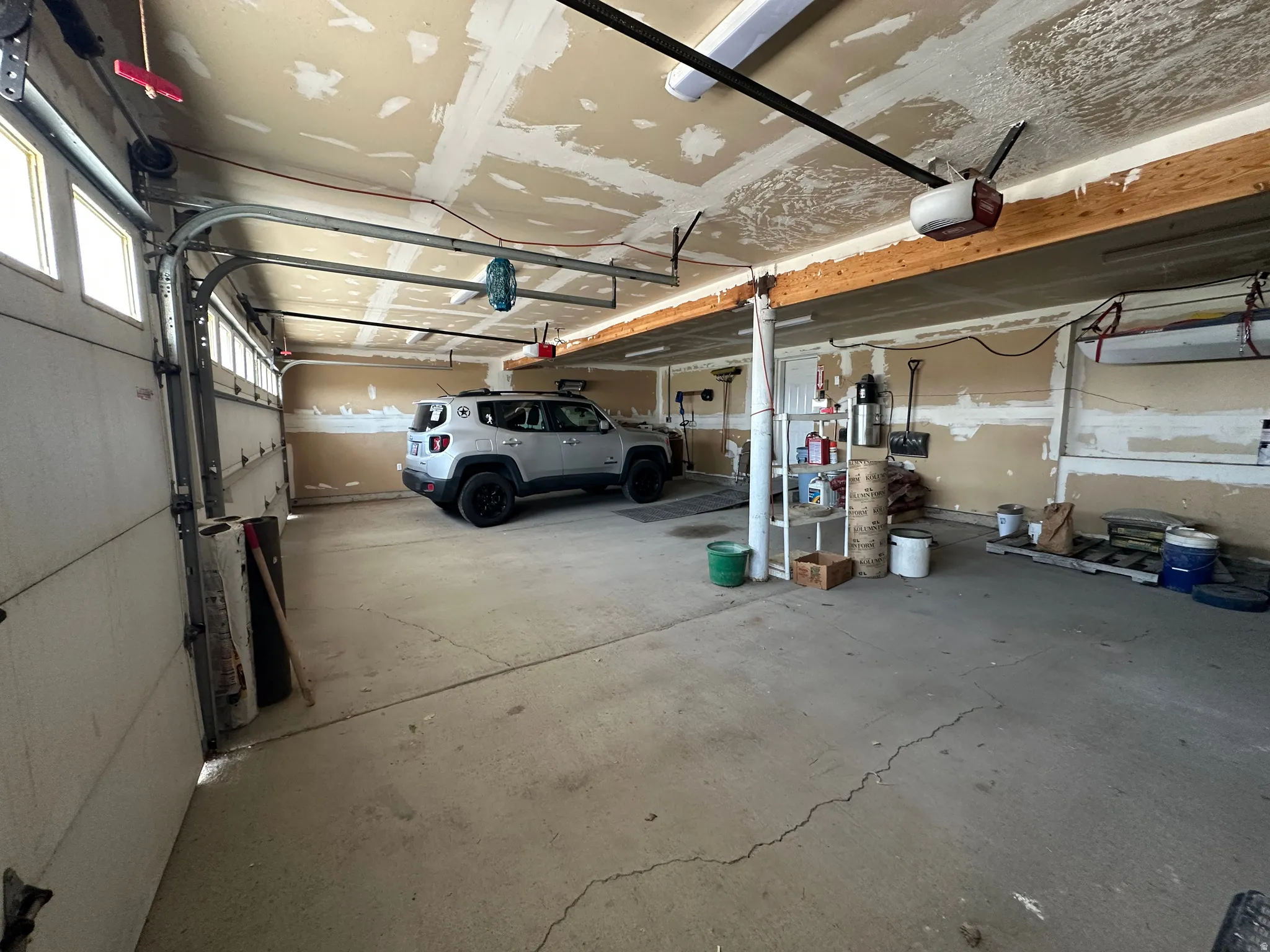 Spacious two-car garage featuring a concrete floor, automatic garage door openers, exposed ceiling joists, and multiple windows for natural light