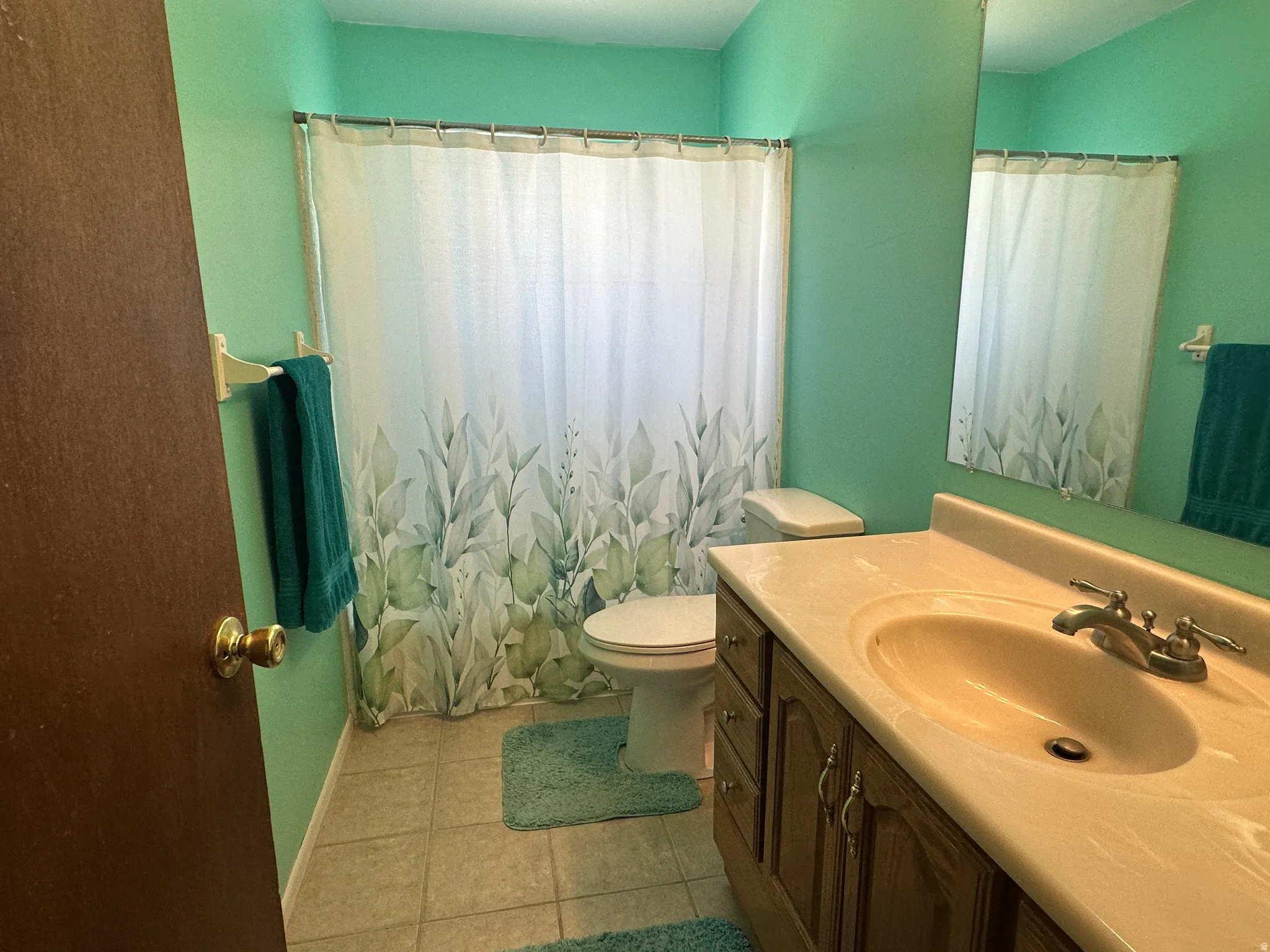 Bathroom featuring a single vanity with an integrated sink, dual-handle faucet, wood-finish cabinetry, and a full-width mirror