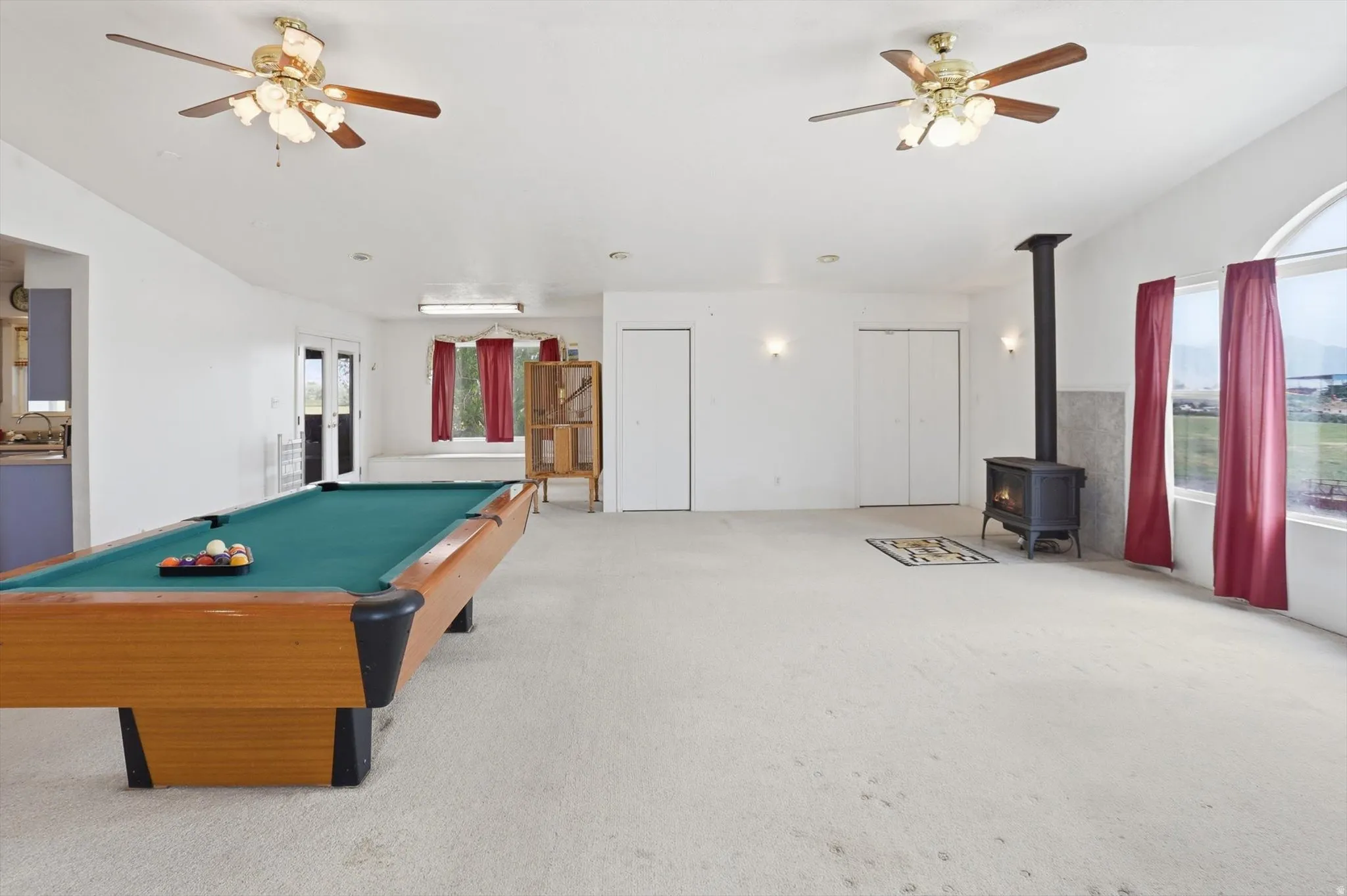 Spacious room with white walls, light-colored carpeting, and two ceiling fans with light fixtures
