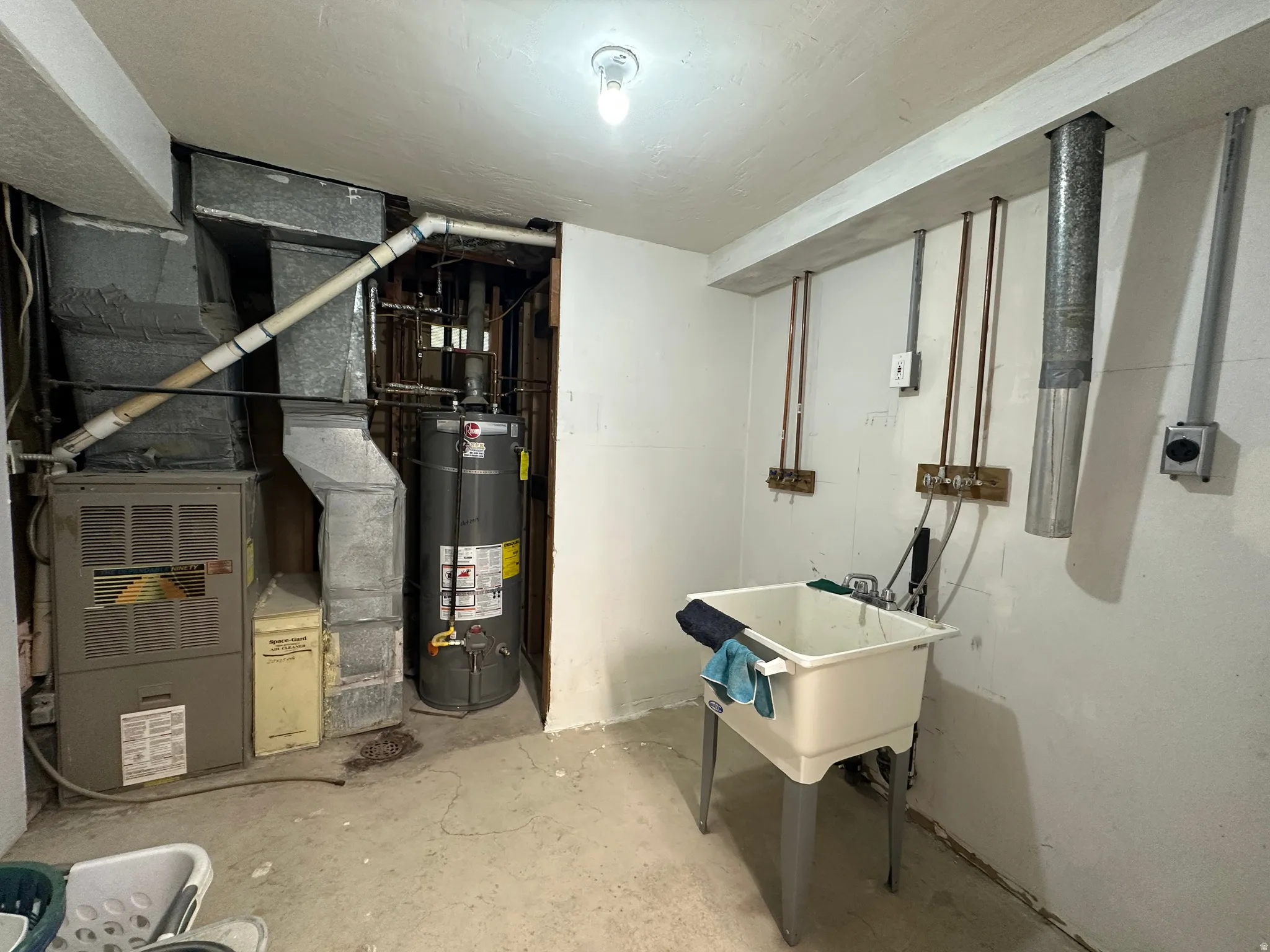 Utility area featuring a laundry sink, exposed copper plumbing, and a hot water heater