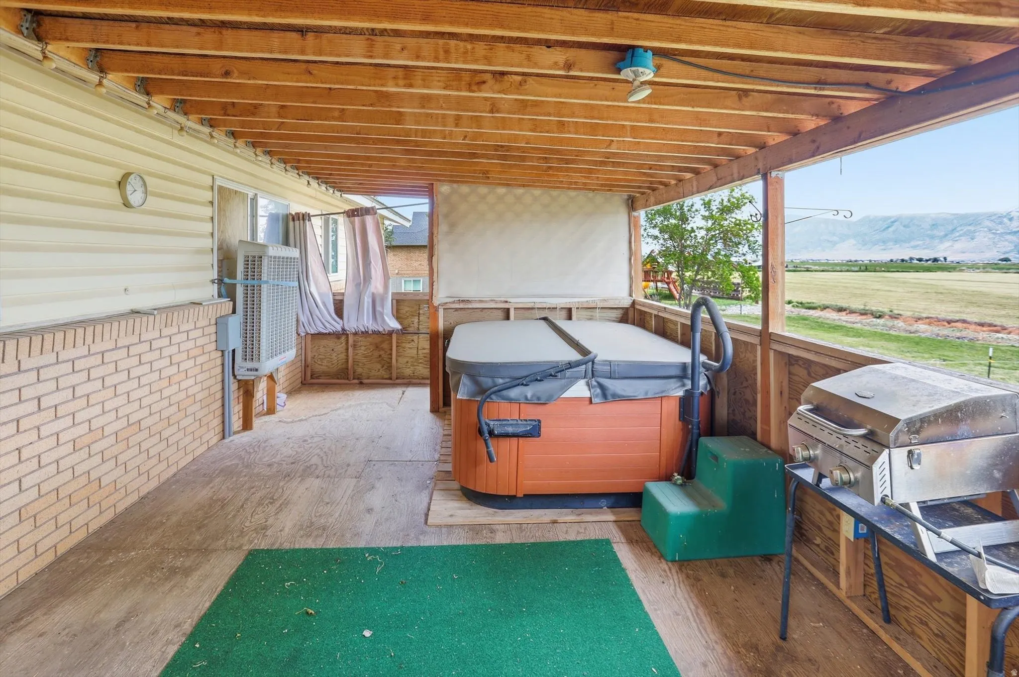 Covered deck featuring an exposed wood beam ceiling and a built-in hot tub