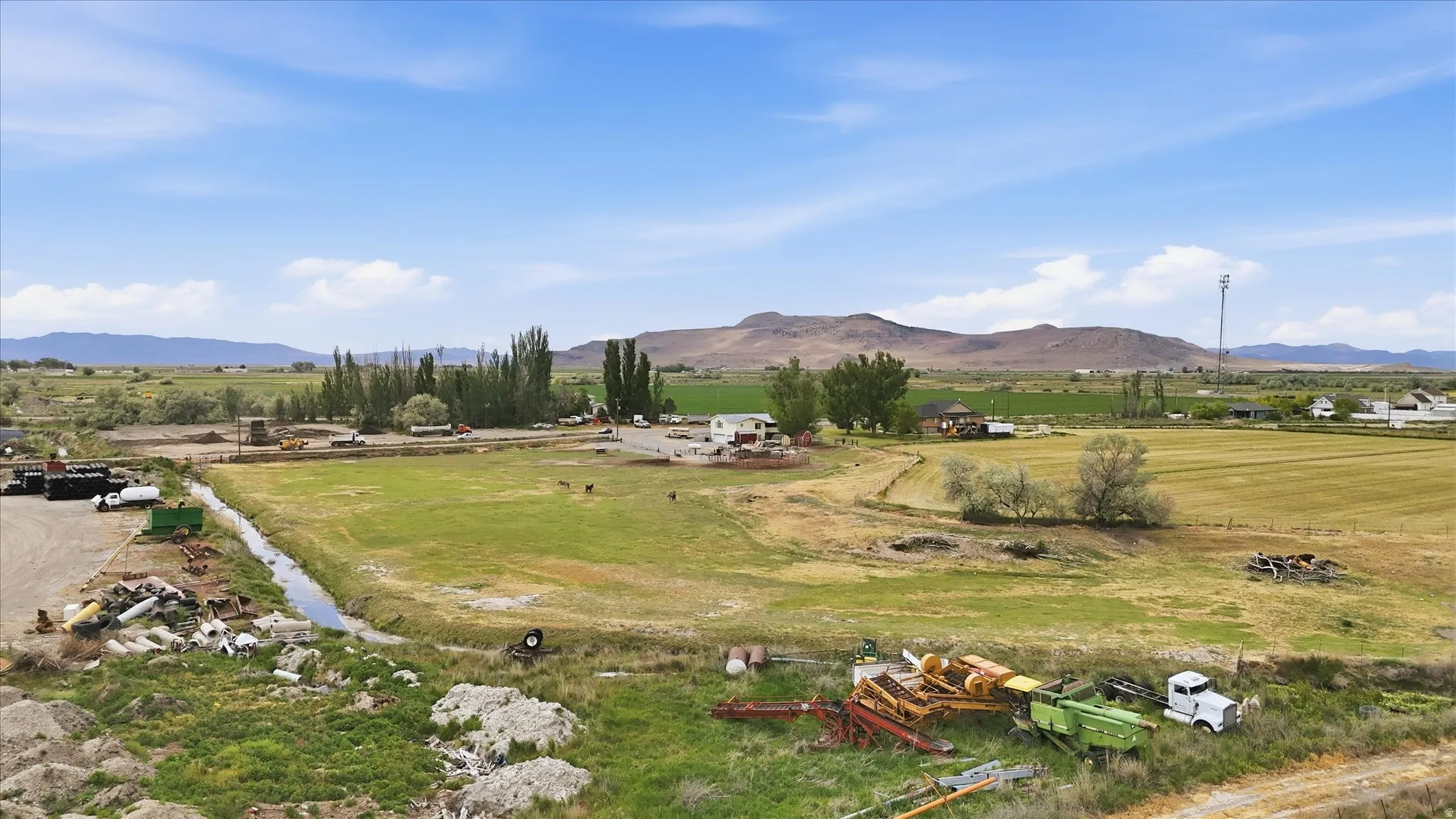 Expansive rural acreage featuring diverse terrain, a visible irrigation ditch, and distant mountain backdrops
