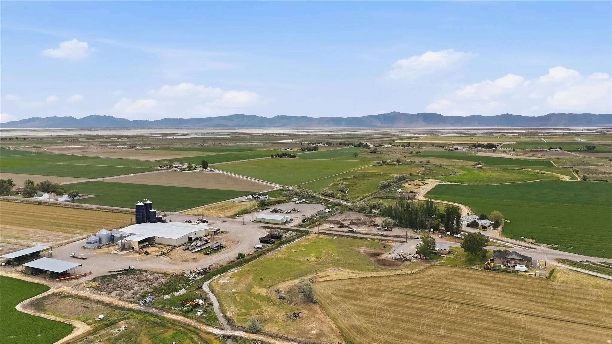 Expansive agricultural property featuring multiple fields, large building with silos, and numerous outbuildings