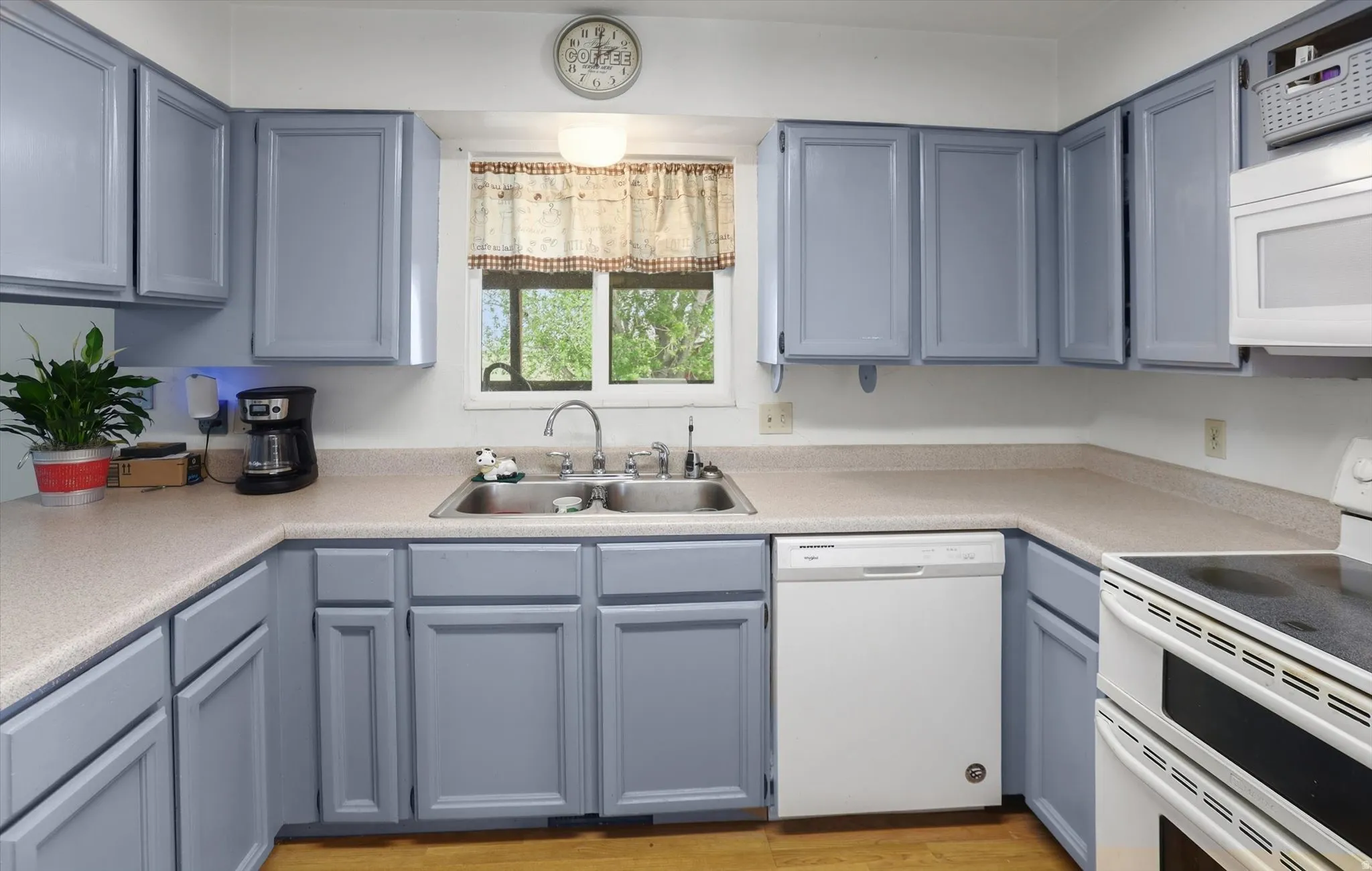 Kitchen featuring light blue cabinetry, light-toned countertops, and wood-finish flooring