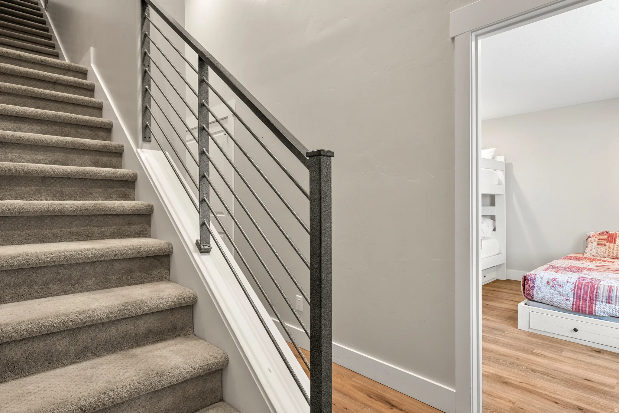 Carpeted staircase with contemporary metal horizontal balusters and a square newel post