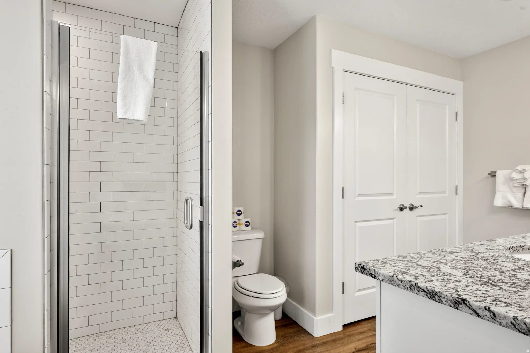Contemporary bathroom featuring a glass-enclosed shower with subway tile surround and mosaic tile flooring