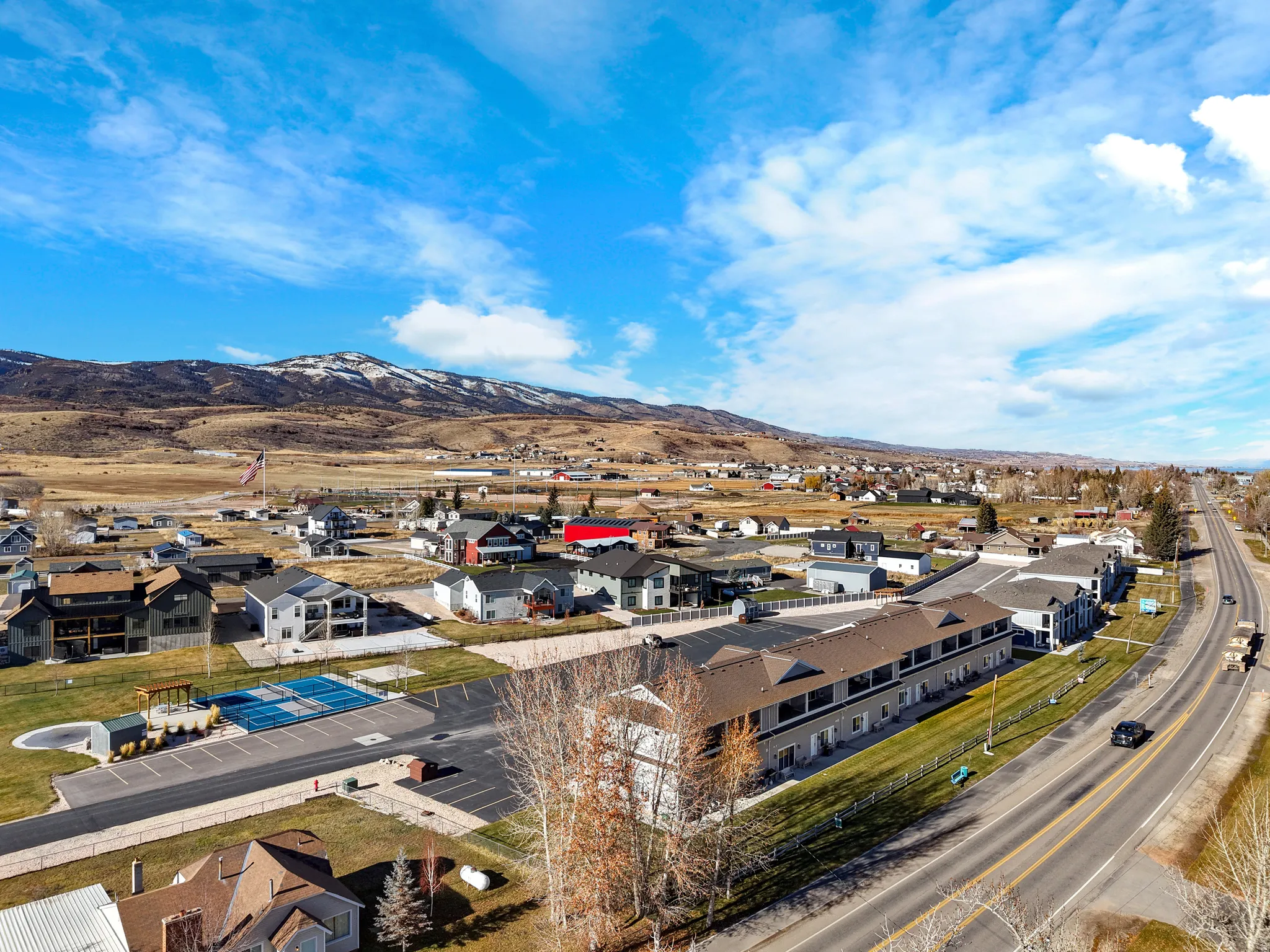 Community setting featuring residential structures, paved roadways, and a distant mountain backdrop