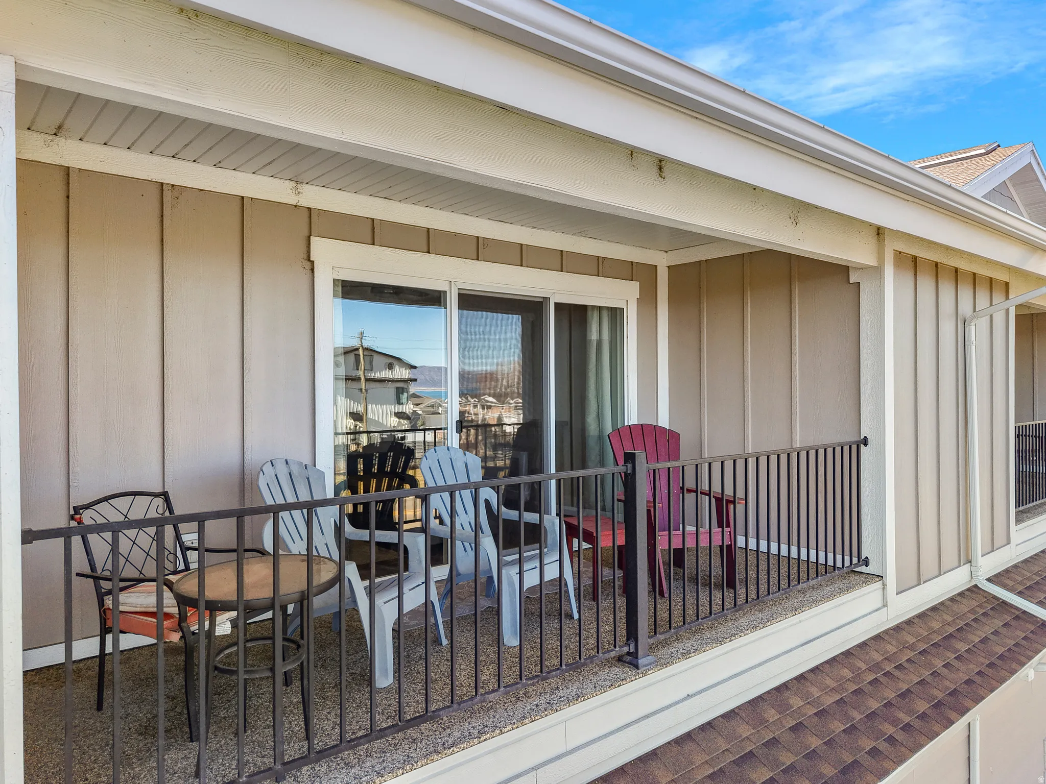 Covered balcony featuring a sliding glass door, textured exterior siding, and a decorative metal railing