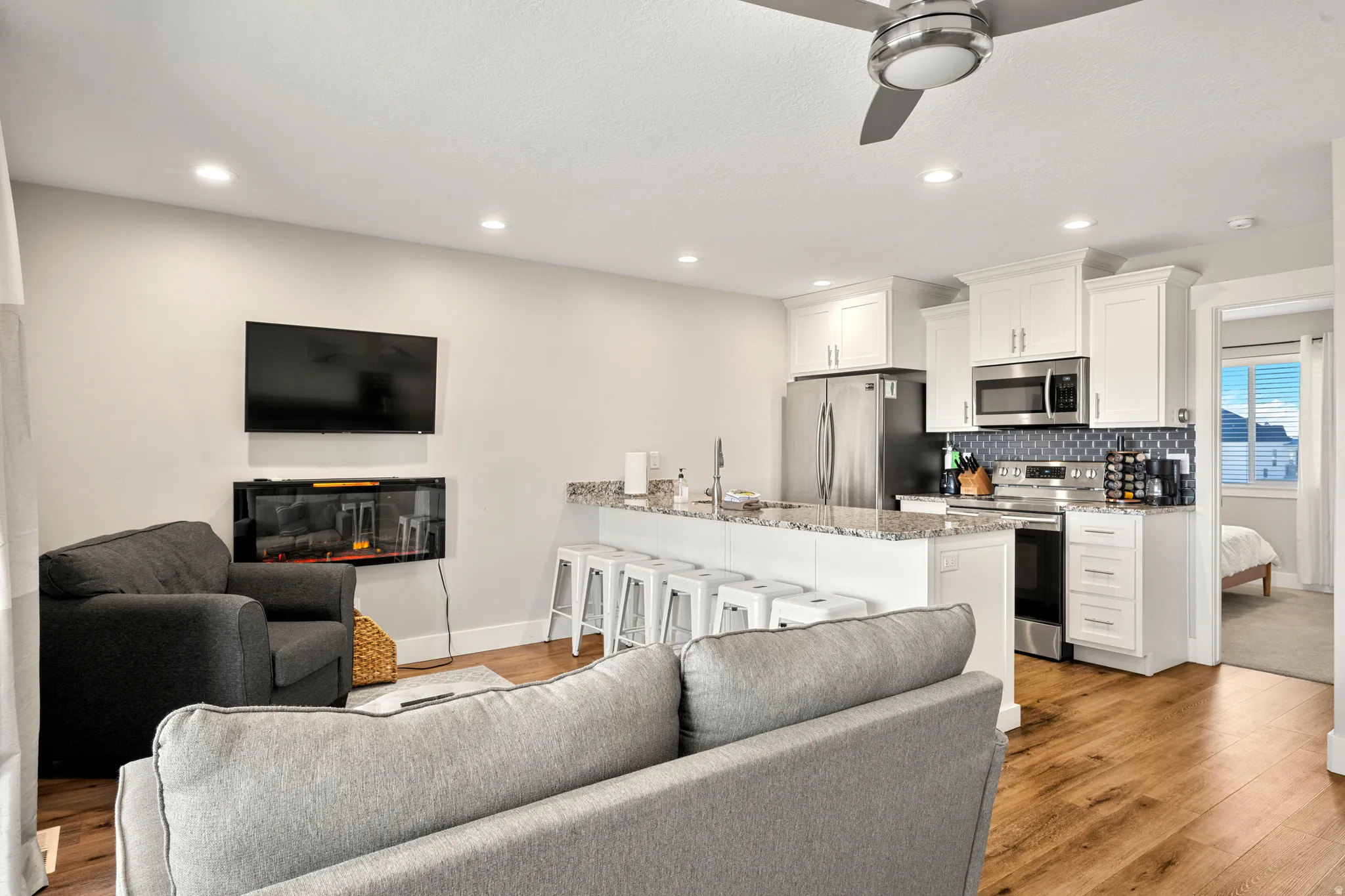 Open-concept living space featuring wood-finish flooring, recessed lighting, and a ceiling fan