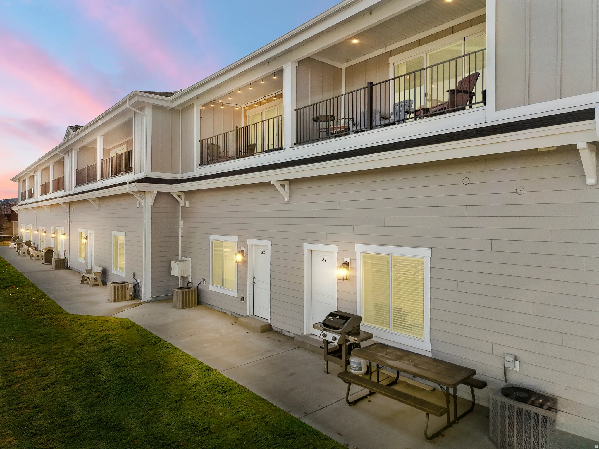 Multi-story building exterior with horizontal siding and upper-level balconies featuring black metal railings