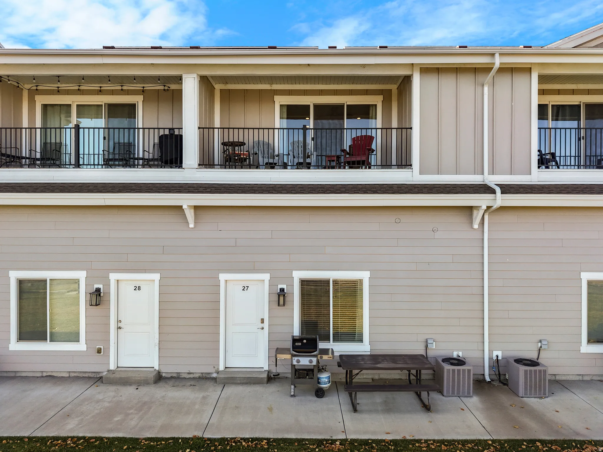 Exterior elevation featuring two private balconies with black metal railings and sliding glass doors