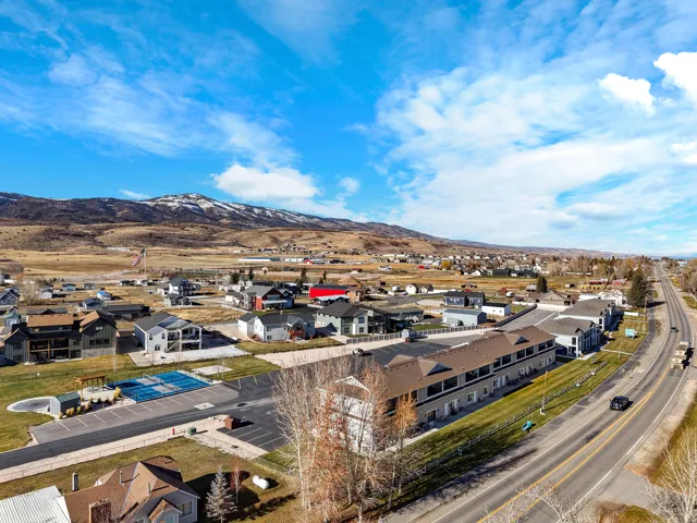 Community setting featuring residential structures, paved roadways, and a distant mountain backdrop