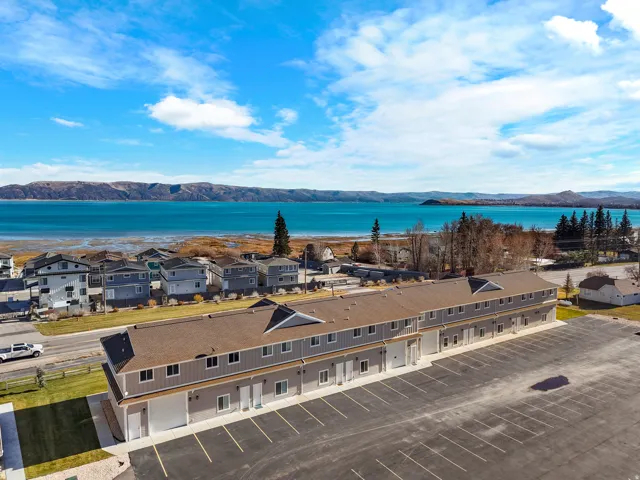 Multi-unit building featuring a contemporary design, ample paved parking, and a brown shingle roof
