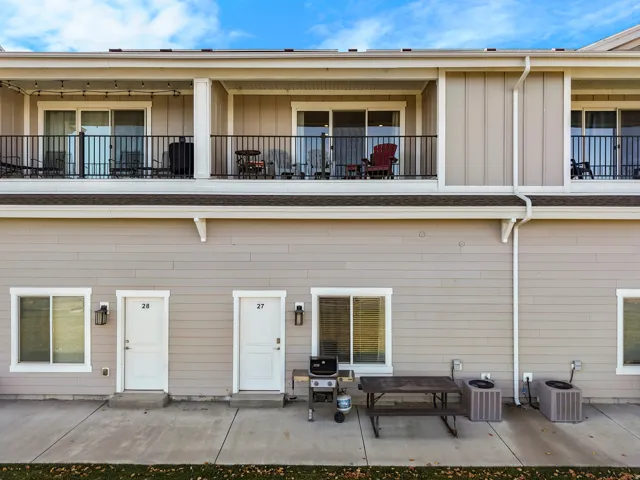 Exterior elevation featuring two private balconies with black metal railings and sliding glass doors
