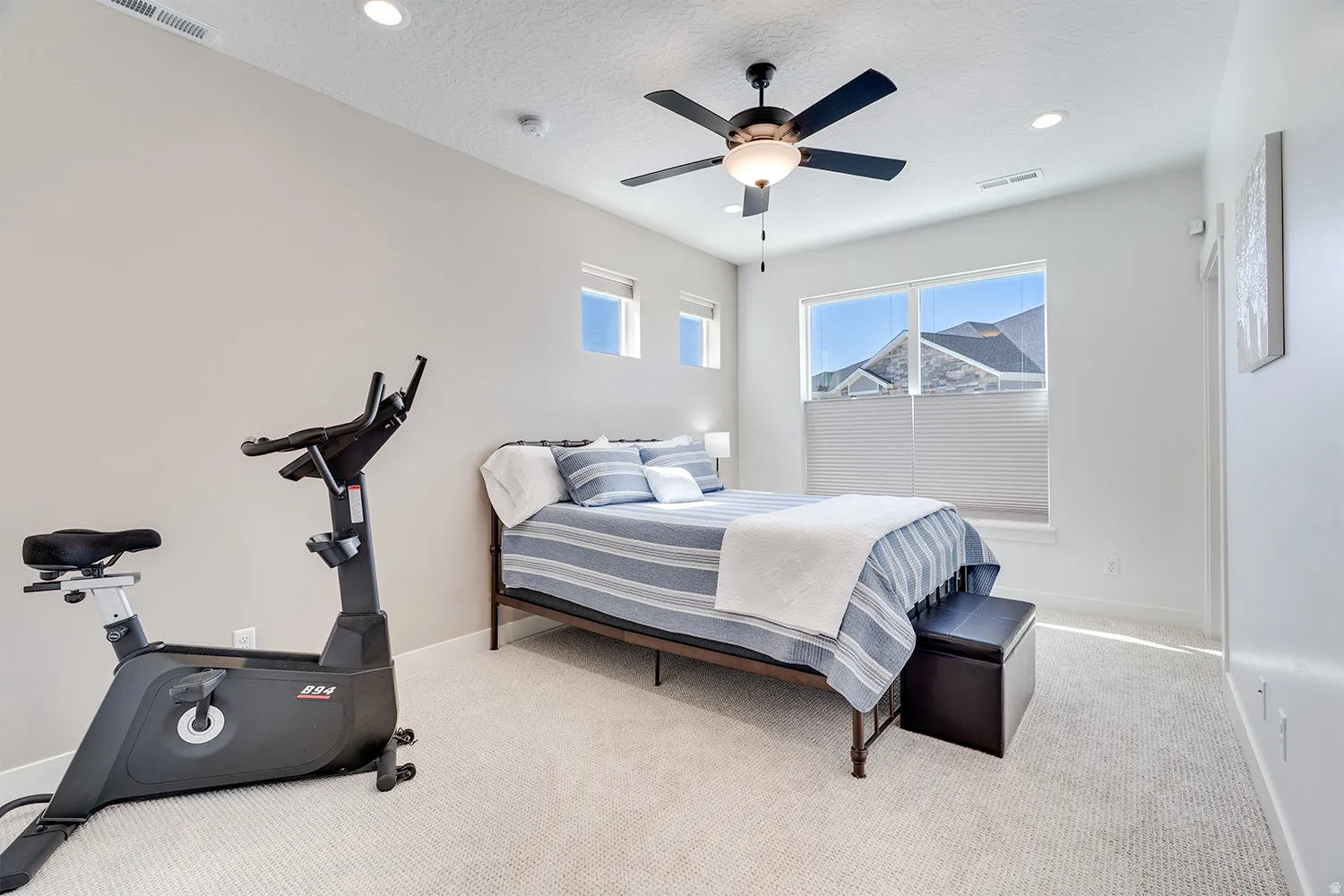 Spacious bedroom featuring light-colored carpet flooring, recessed ceiling lighting, a ceiling fan, and multiple windows with blinds for ample natural light
