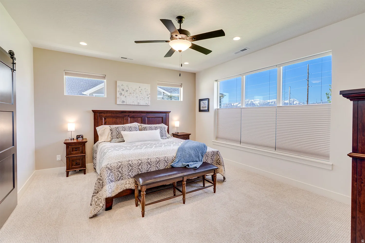 Carpeted room featuring a ceiling fan with integrated lighting, recessed lighting, and a barn door