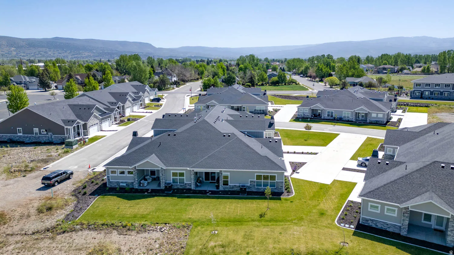 Residential community featuring a variety of single-story homes with dark shingle roofs, light gray siding, and stone accents