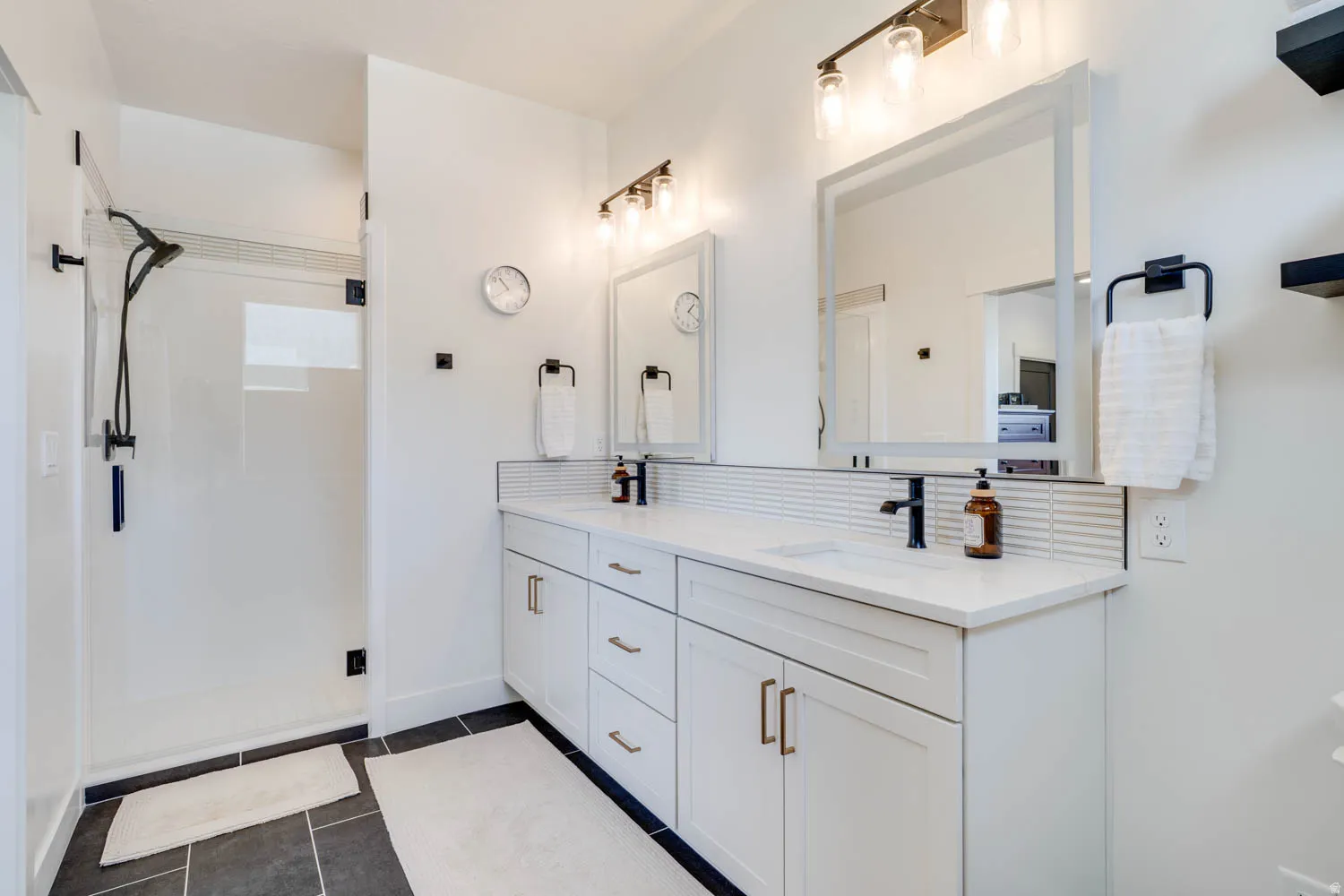 Double vanity with undermount sinks and white countertops, featuring matte black faucets and light fixtures