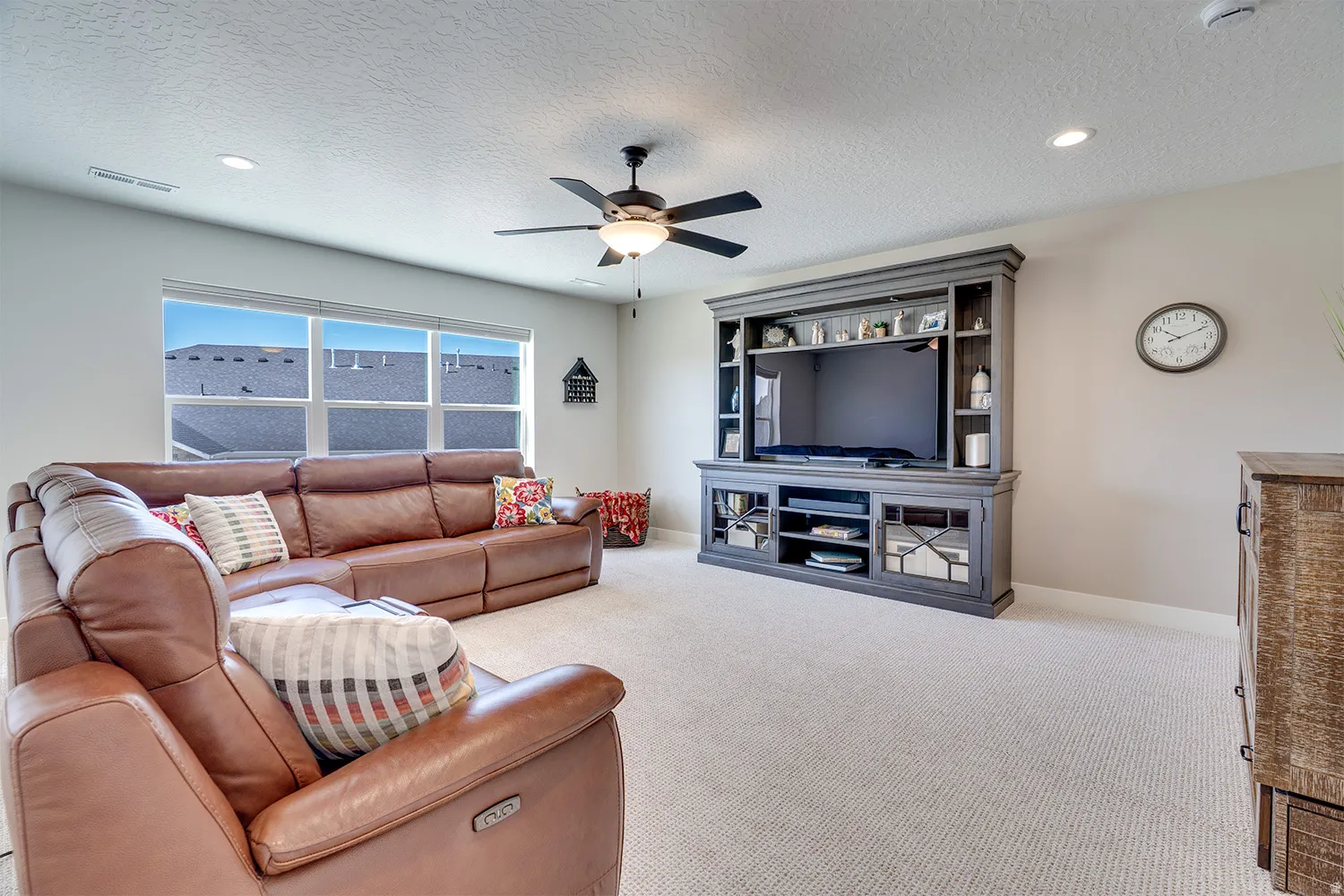 Spacious living area featuring neutral carpeting, a multi-pane window, recessed lighting, and a ceiling fan