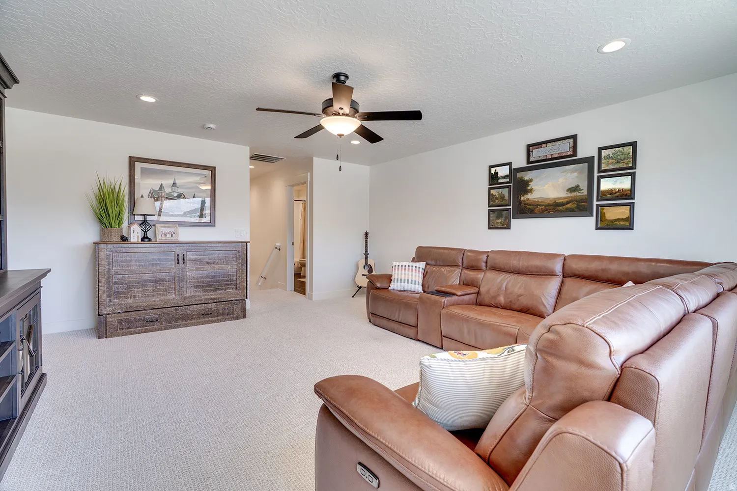Spacious carpeted room featuring a ceiling fan with integrated lighting, recessed lighting, and a built-in wall unit