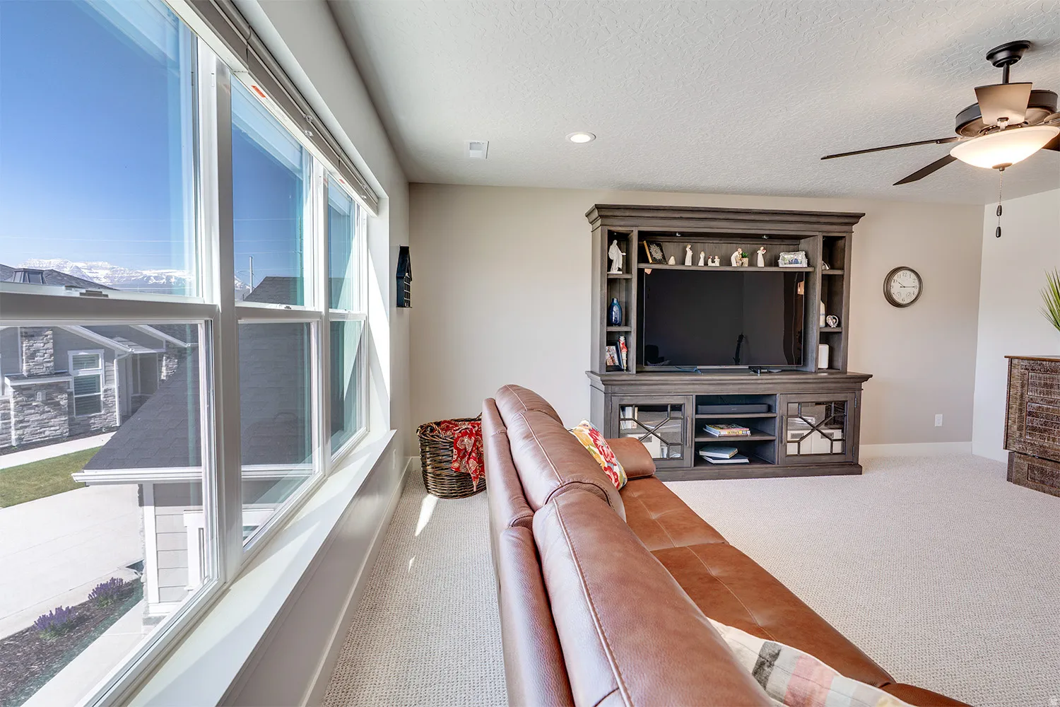 Expansive window bank providing abundant natural light, neutral wall colors, recessed lighting, ceiling fan with integrated light fixture, and carpeted flooring