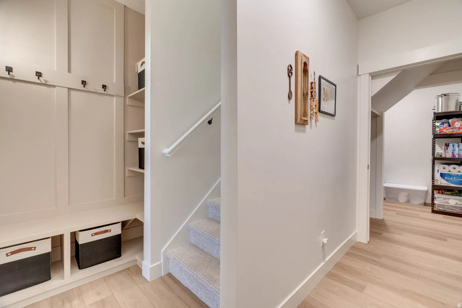 Built-in mudroom bench with coat hooks and integrated shelving, featuring wood-finish flooring