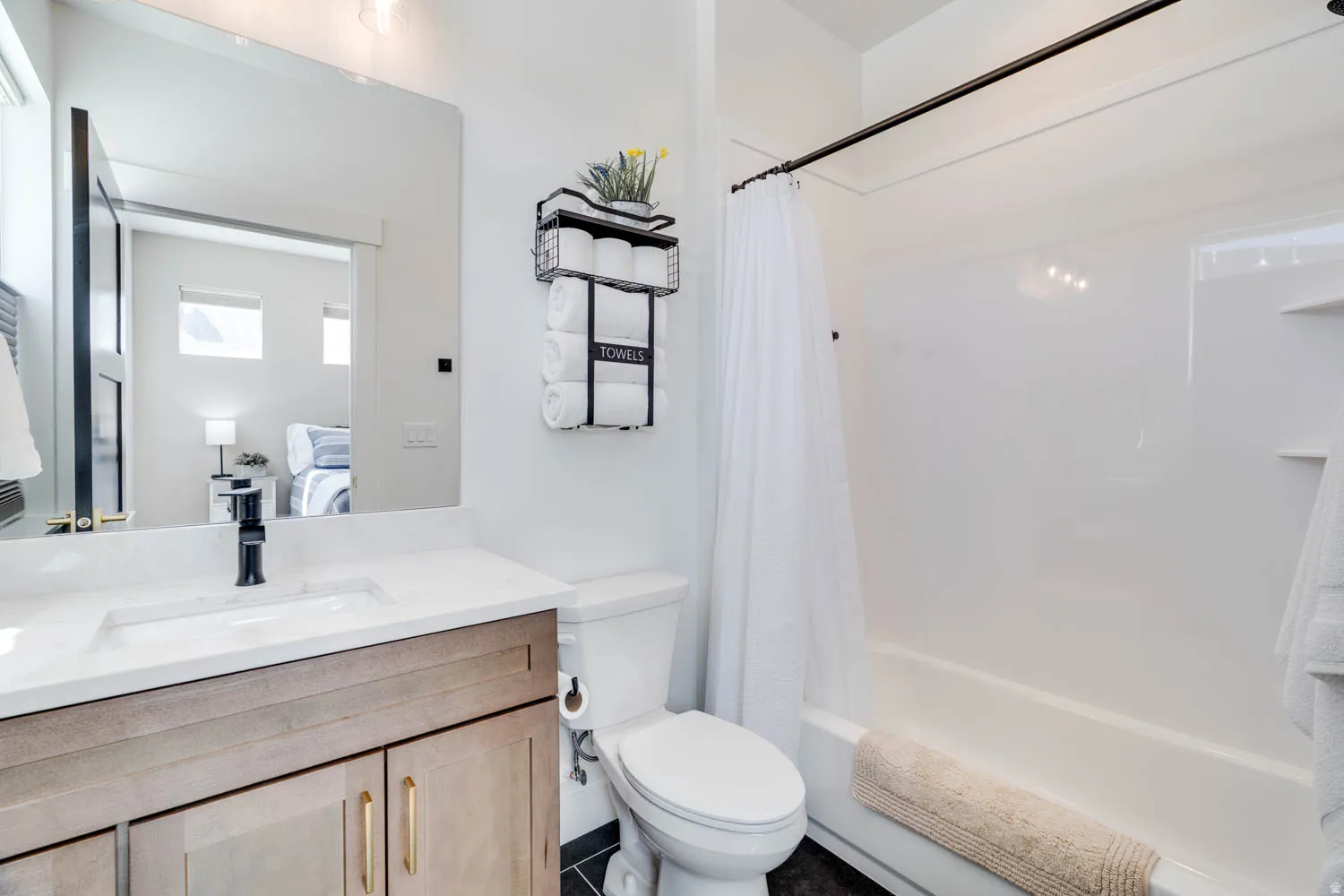 Bathroom featuring a wood-finish vanity with gold-tone hardware, rectangular undermount sink, and a white countertop