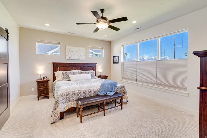 Carpeted room featuring a ceiling fan with integrated lighting, recessed lighting, and a barn door