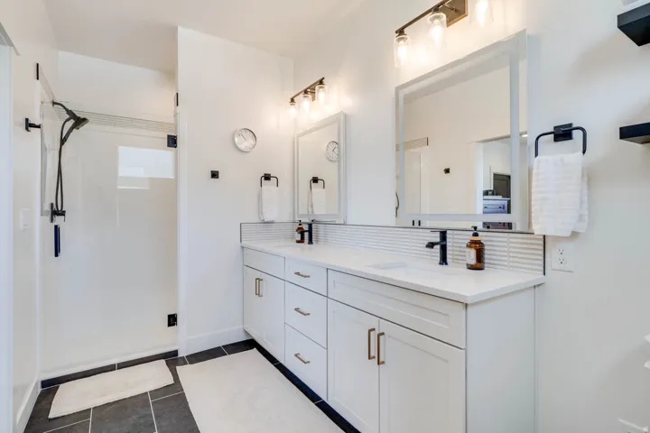 Double vanity with undermount sinks and white countertops, featuring matte black faucets and light fixtures