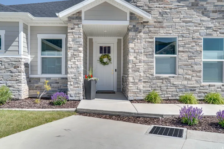 Contemporary facade featuring light grey siding and stacked stone accents