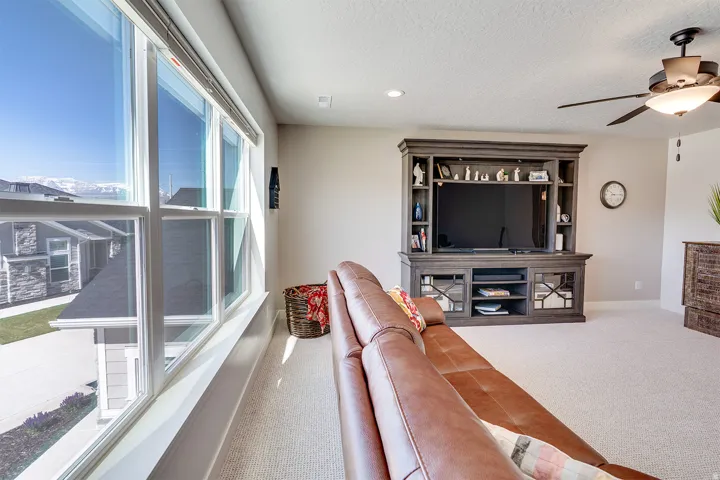 Expansive window bank providing abundant natural light, neutral wall colors, recessed lighting, ceiling fan with integrated light fixture, and carpeted flooring