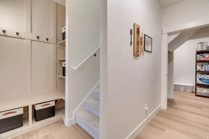 Built-in mudroom bench with coat hooks and integrated shelving, featuring wood-finish flooring
