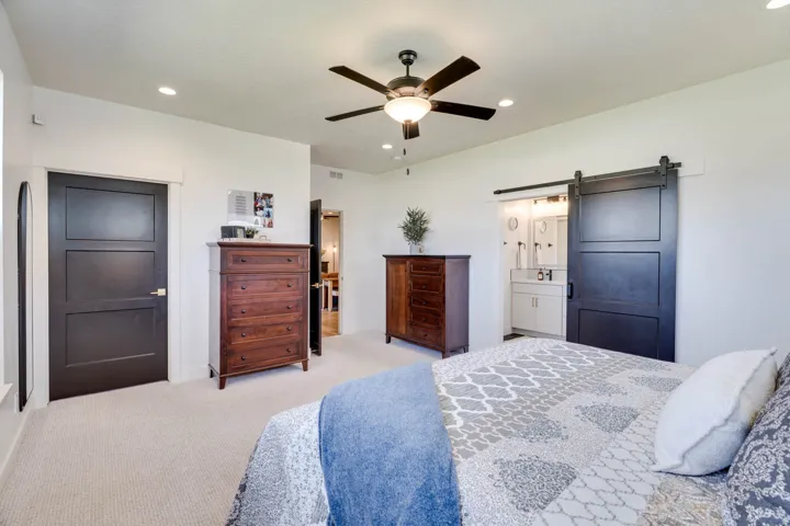 Carpeted room featuring a ceiling fan with integrated lighting, recessed lighting, and a dark-paneled door