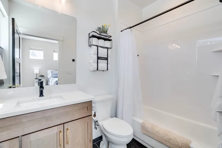 Bathroom featuring a wood-finish vanity with gold-tone hardware, rectangular undermount sink, and a white countertop