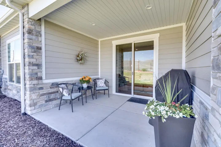 Exterior patio featuring concrete flooring, stone veneer accents, horizontal siding, a large window, and a sliding glass door