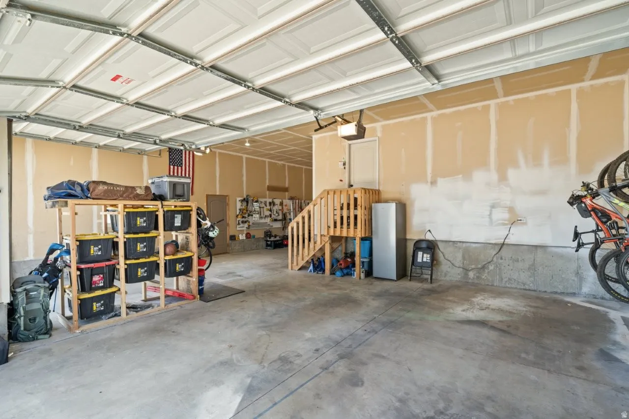 Spacious garage featuring a concrete floor, exposed ceiling joists, and a partial wood staircase