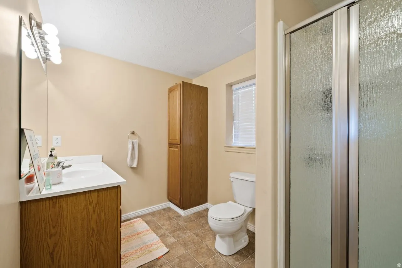 Bathroom featuring a wood-finish vanity with an integrated sink, white countertop, and a vanity mirror with a decorative light fixture