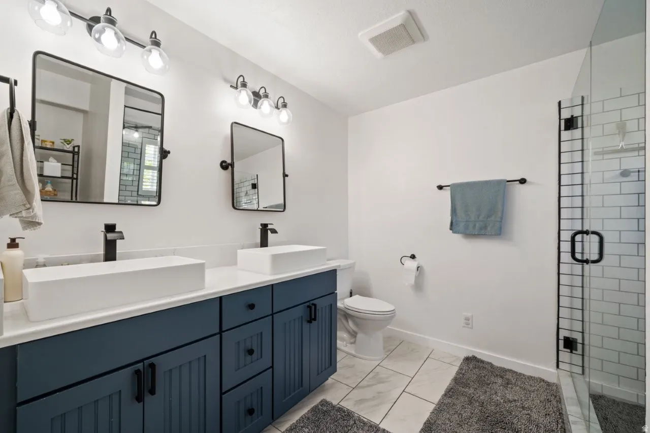 Dual vessel sinks with matte black fixtures, set on a dark blue vanity with shaker-style cabinetry